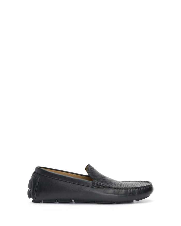 The Men’s Eadric Casual Driving Shoe by Vince Camuto is a black leather loafer featuring a textured upper, visible stitching, and a flat rubber sole. Presented in a side profile against a white background, this shoe is ideal for anyone seeking comfortable footwear that doesn’t sacrifice style.