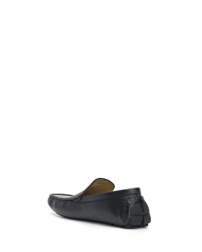 The Vince Camuto Men’s Eadric Casual Driving Shoe is displayed from both the back and side angles, showcasing its textured rubber heel and sleek, smooth finish. Set against a white background, this shoe represents a blend of style and comfort.