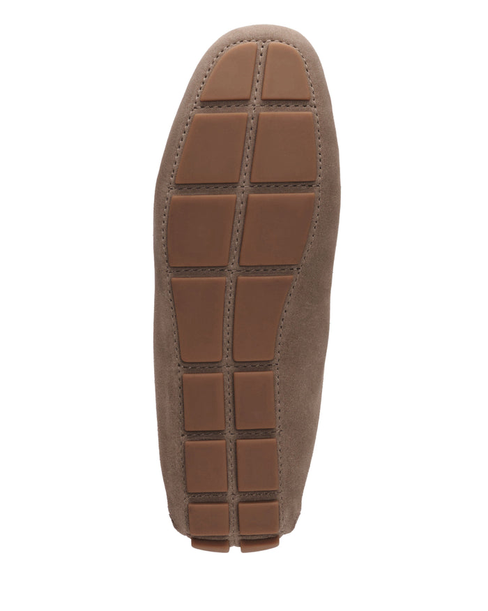 The image shows the sole of a brown suede Vince Camuto Men’s Eadric Casual Driving Shoe, featuring rectangular rubber grip sections arranged in a grid pattern—demonstrating the brand’s blend of elegant style and comfortable design.
