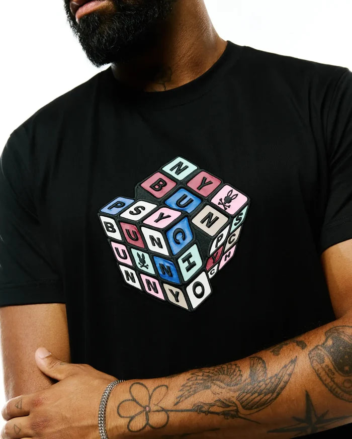 Black Mens Eddy Graphic Tee, classic fit, smooth jersey, with a large, textured 3D cube graphic on the chest spelling PSYCHO BUNNY in multi-colored blocks, featuring the iconic bunny skull logo.