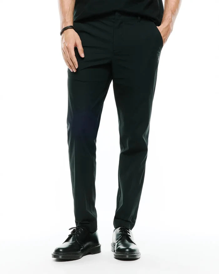 Mens Edward 10k Tapered Pant in dark green, featuring a slim tapered fit and smooth performance fabric, with a small embroidered Psycho Bunny skull logo on the upper right thigh.