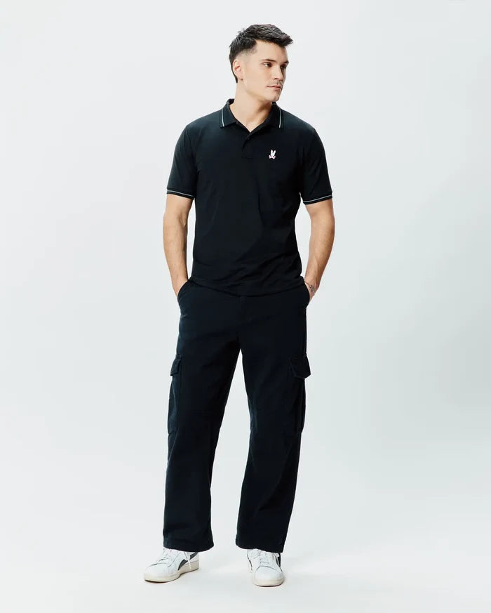 Mens Edwin Sport Polo, black pique knit polo shirt with a classic fit, featuring white piping on the collar and sleeve cuffs, and a small white embroidered Psycho Bunny skull logo on the left chest.