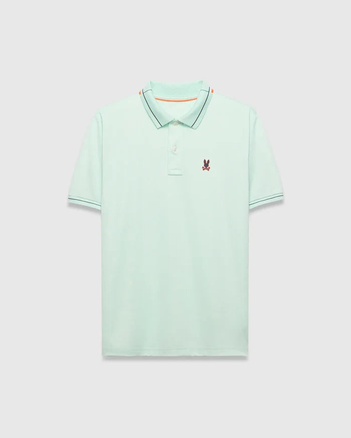Mens Edwin Sport Polo, a classic fit light green pique polo with a black and orange striped collar, matching black striped cuffs, and a small embroidered Psycho Bunny skull logo on the left chest.
