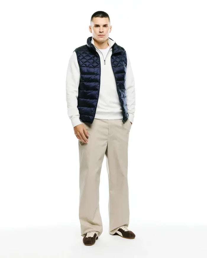 Mens Emerik Quilted Puffer Vest in navy, featuring a diamond quilted pattern, full zip front, stand collar with white lining, and a small Psycho Bunny skull logo on the zipper pull. Classic fit.