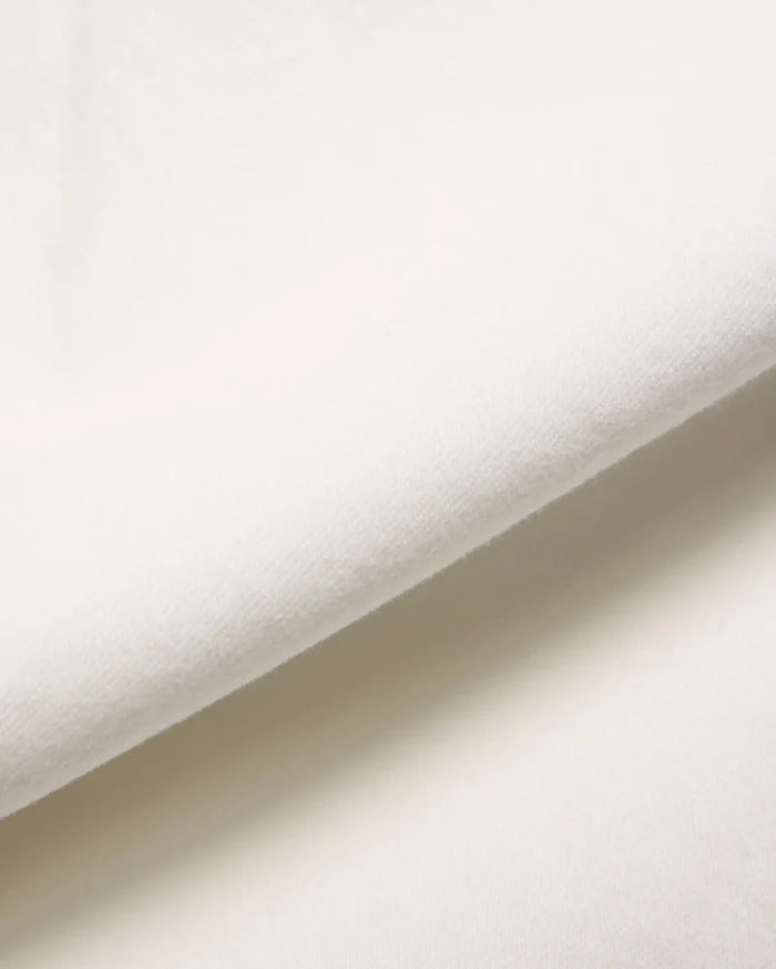 Mens Emerson Denim Pant in a crisp, creamy white, showcasing a premium, soft-touch denim fabric with a subtle, refined twill weave, gently folded to reveal its luxurious texture.