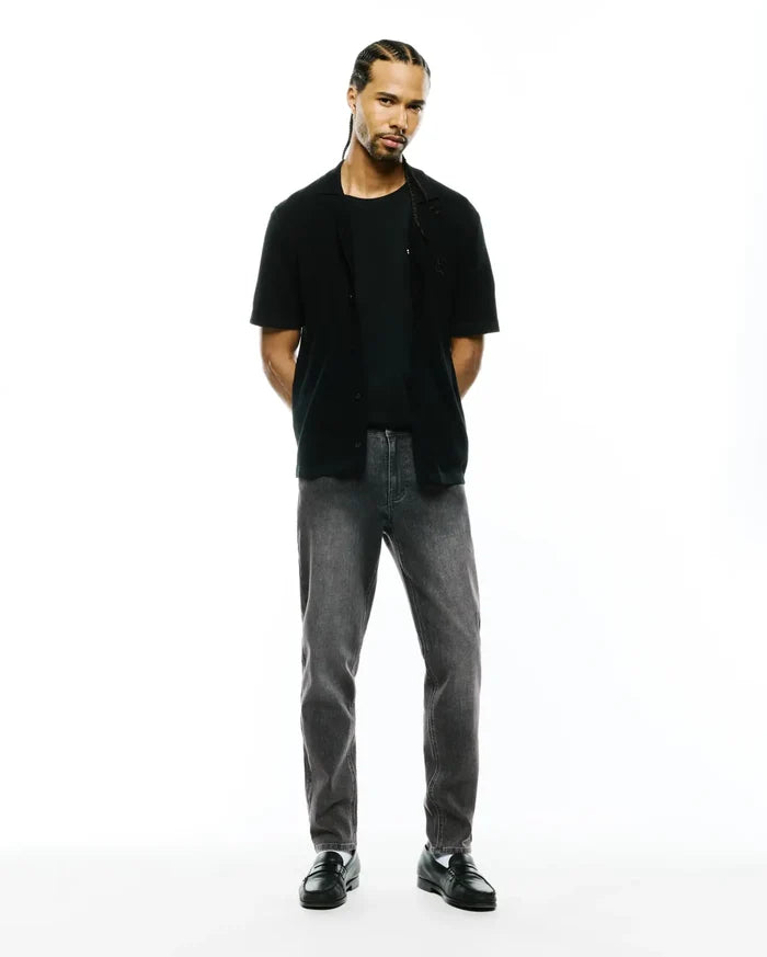 Black jersey t-shirt, black relaxed short-sleeve shirt with small embroidered Psycho Bunny skull on left chest, and Mens Emerson Denim Pant in dark grey wash.