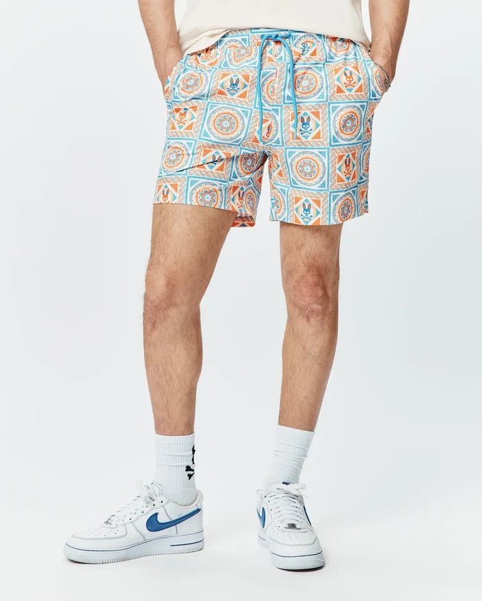 Mens Frank Swim Trunk 6, white with a vibrant orange and blue tiled pattern featuring circular motifs and the iconic Psycho Bunny skull logo, finished with a blue drawstring.