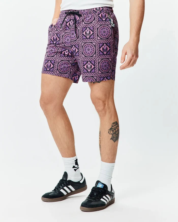 Mens Frank Swim Trunk 6, classic-fit swim shorts in vibrant purple with a black geometric tile pattern, featuring integrated Psycho Bunny skull logos and a drawstring waist with a small bunny charm.