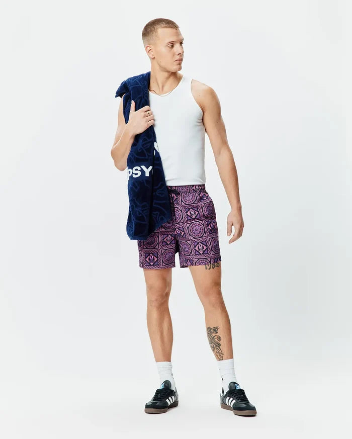 Mens Frank Swim Trunk 6 in lilac and dark purple, featuring a relaxed fit and an all-over geometric pattern with integrated Psycho Bunny skull logos and a black drawstring.