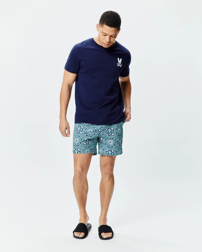 Navy classic fit jersey T-shirt with a small white embroidered Psycho Bunny skull logo on the chest, paired with Mens Frank Swim Trunk 6 featuring a teal and aqua geometric pattern with integrated bunny skull logos.