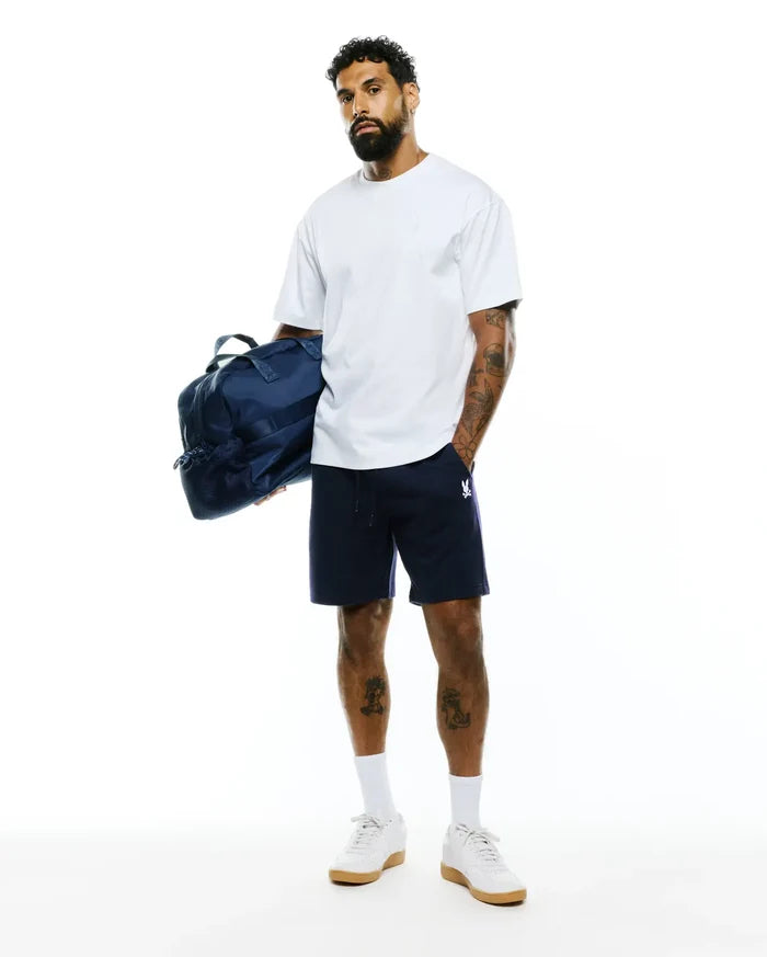 White relaxed fit t-shirt with a small embroidered Psycho Bunny logo on the chest, paired with navy Mens Gabe French Terry Sweatshort featuring a drawstring waist and a white embroidered bunny skull logo on the left leg.