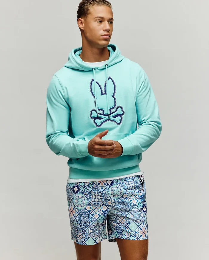 Mens Gage Patch Hoodie, an aqua French terry classic fit hoodie with a large embroidered dark blue and light blue Psycho Bunny skull logo on the chest, featuring a drawstring hood and kangaroo pocket.