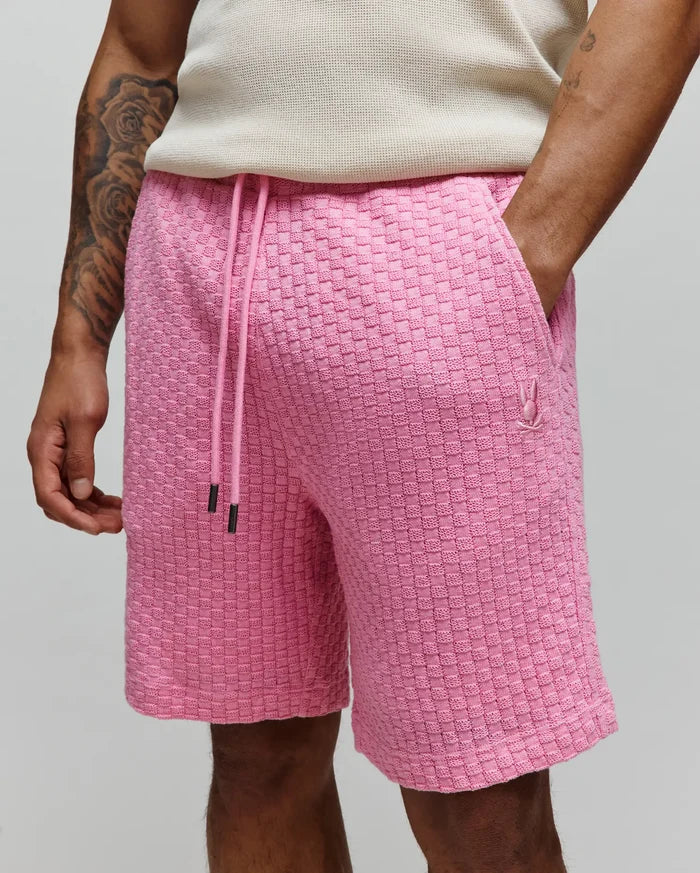 Mens Garen Knit Short in vibrant pink, featuring a relaxed fit, textured basketweave knit fabric, adjustable pink drawstring with black tips, and a small embroidered Psycho Bunny skull logo on the left thigh.