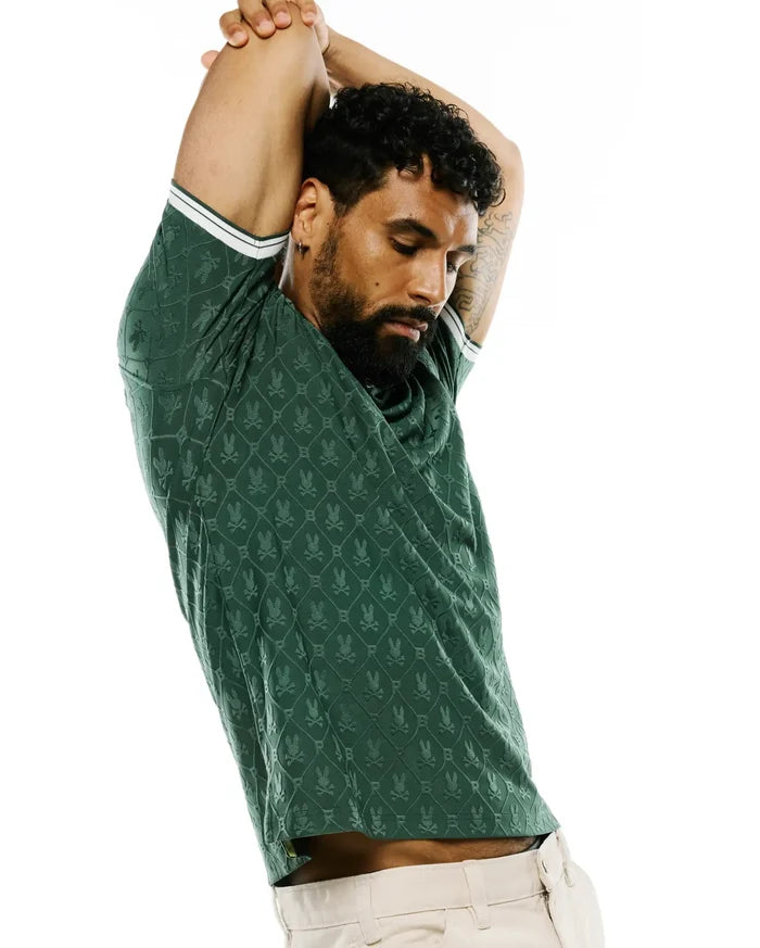 Mens Garry Jacquard Johnny Collar Polo in dark green, featuring an all-over jacquard Psycho Bunny skull logo pattern in a diamond grid, slim fit, and white double-stripe trim on sleeve cuffs.