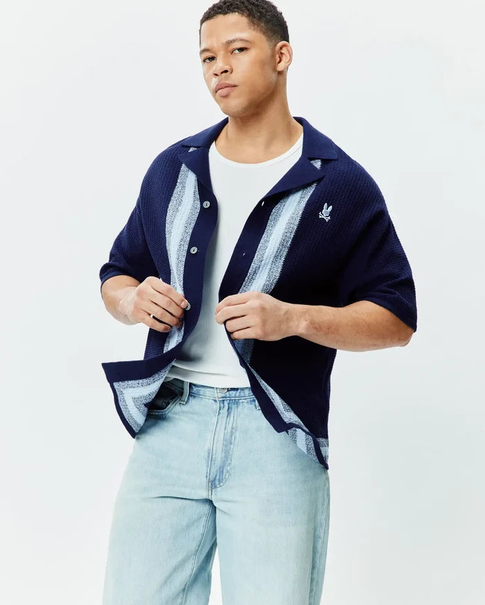 Mens Giles Relaxed Fit Border Knit Shirt in navy with light blue and white vertical stripes, featuring a textured knit fabric and a small embroidered Psycho Bunny skull logo on the left chest.