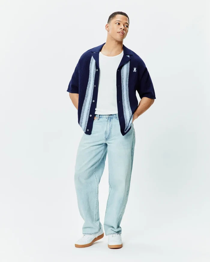 Mens Giles Relaxed Fit Border Knit Shirt in navy with light blue and white vertical stripes, featuring a visible knit texture and a small embroidered white Psycho Bunny skull logo on the left chest.