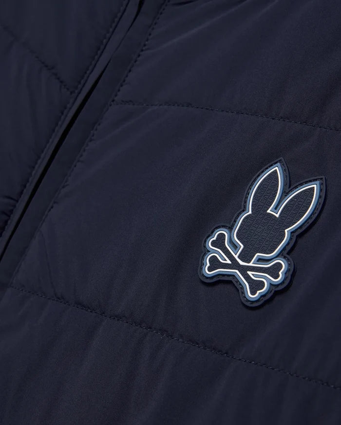 Mens Gordley Mix Media Jacket in navy blue, featuring a quilted left panel and smooth right panel, with a prominent Psycho Bunny skull and crossbones logo on the chest, detailed with white and light blue accents and embossed brand lettering.