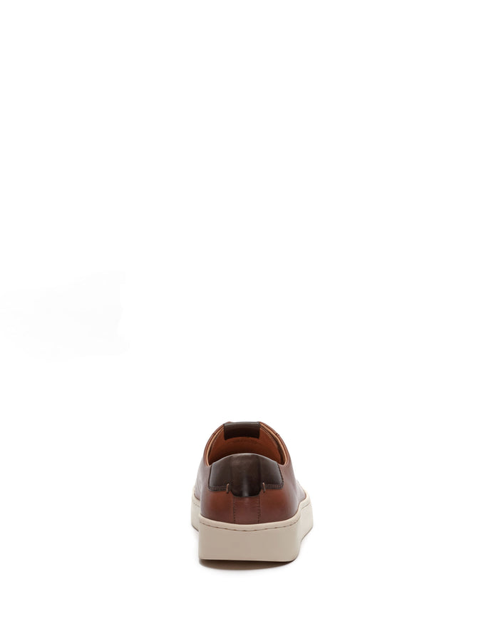 Introducing the Men’s Hallman Casual Sneaker by Vince Camuto—a stylish brown leather sneaker featuring a sleek white sole. Photographed from the back against a white background, these sneakers blend modern style with all-day comfort in one refined design.