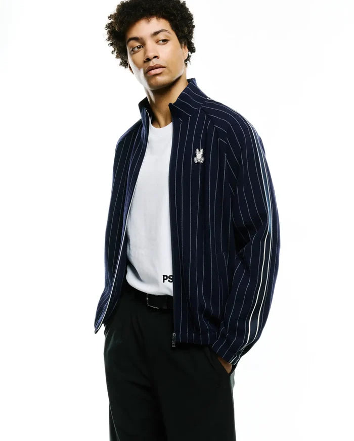 Mens Harland Double Weave Chalk Stripe Track Jacket, navy blue with white vertical chalk stripes, full zip, small embroidered Psycho Bunny skull logo on left chest, and white double stripes on sleeves.