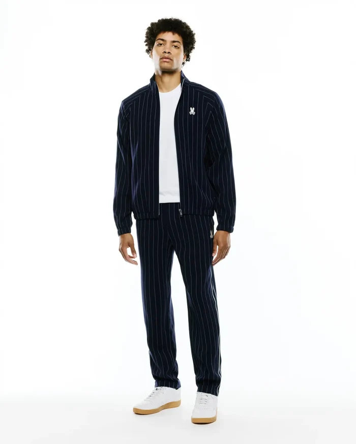 Mens Harland Double Weave Chalk Stripe Track Jacket and matching pants in navy with white vertical chalk stripes. Features a classic fit, full-zip jacket, and small embroidered white Psycho Bunny skull logos on the left chest and left thigh.