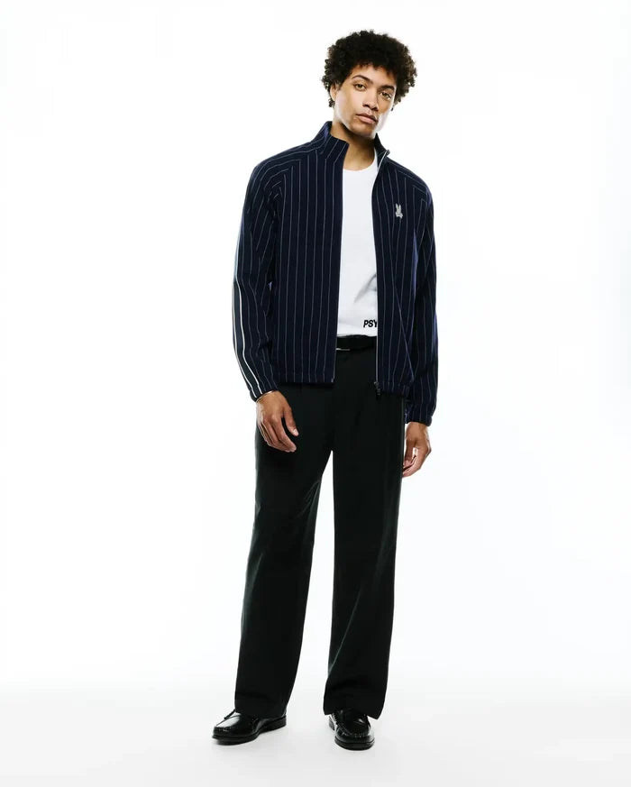 Mens Harland Double Weave Chalk Stripe Track Jacket in navy with white vertical pinstripes, a full zip, stand collar, and a small embroidered Psycho Bunny skull logo on the left chest, featuring white accent stripes on the sleeves.