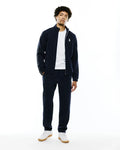 Mens Harland Double Weave Chalk Stripe Track Pant and matching full-zip jacket. Navy blue relaxed fit tracksuit with white pinstripes, green sleeve stripe, and embroidered Psycho Bunny skull logo.