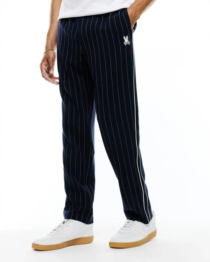 Harland Double Weave Chalk Stripe Track Pant in navy with white pinstripes, featuring a white and light green side stripe and a small embroidered white Psycho Bunny skull logo on the left thigh, classic fit.
