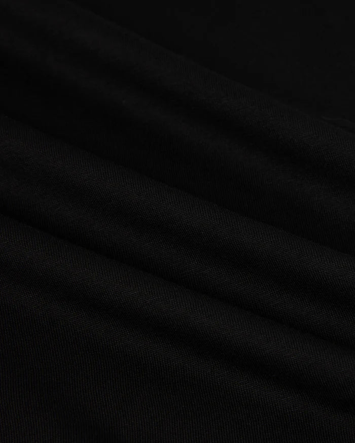 Close-up of the MENS HAWAII CITY TEE - B6U169Y1PC by Psycho Bunny, made from black Pima cotton fabric with a smooth, slightly rippled texture. The dark material displays gentle folds and a subtle sheen, resembling the luxurious quality of a sophisticated men's T-shirt for an elegant appearance.