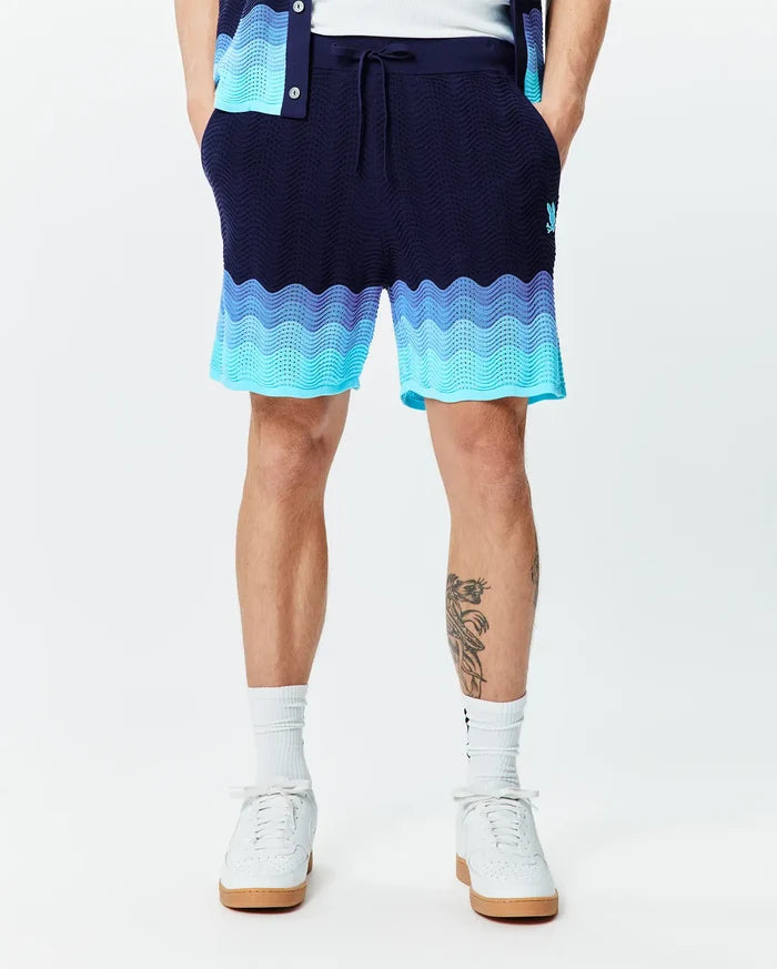 Mens Holden Knit Short 6 in navy blue with a wavy knit texture, featuring an ombre transition to light blue and turquoise, and a small embroidered Psycho Bunny skull logo on the right thigh.