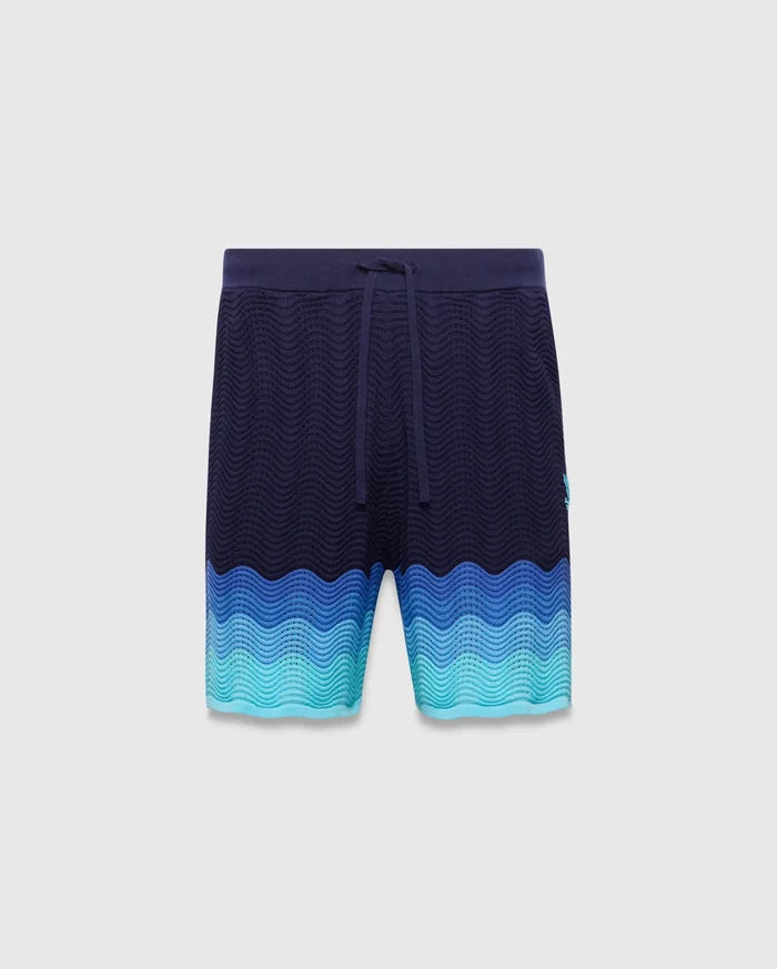 Holden Knit Short 6, navy relaxed fit shorts with a wavy knit texture, transitioning to blue and teal gradient, drawstring waist, and small embroidered Psycho Bunny skull logo on left leg.