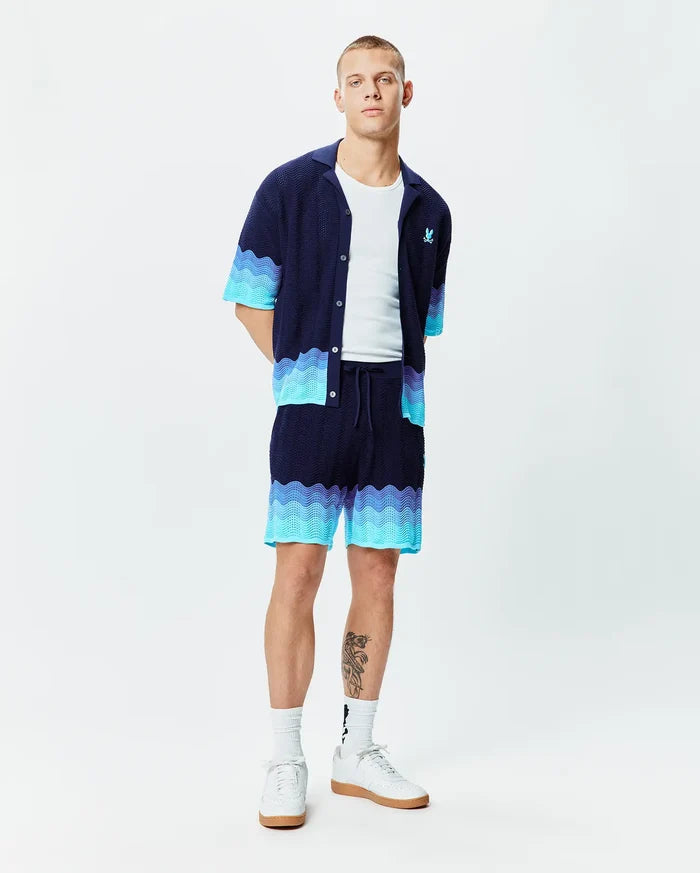 Mens Holden Oversized Knit Shirt and matching shorts in navy blue, featuring a relaxed knit texture with wavy gradient light blue and turquoise accents, and a small light blue Psycho Bunny skull logo on the left chest.