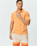 Mens Holden Pique Polo, vibrant orange pique knit, classic fit, with white striped collar and cuffs, featuring a small embroidered Psycho Bunny skull logo.