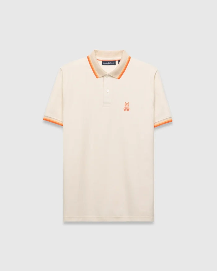 Mens Holden Pique Polo, cream classic fit with textured pique fabric, featuring an orange embroidered Psycho Bunny skull logo on the left chest, and ribbed collar/cuffs with orange and beige stripes.