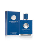 A blue bottle of Vince Camuto Men’s Homme 3.4 oz Eau de Toilette Spray is presented alongside a matching blue box. This sophisticated fragrance is infused with notes of blue cypress and pressed citron. Both the upright bottle and the box are adorned with silver emblem and text, with the box displaying the product details.