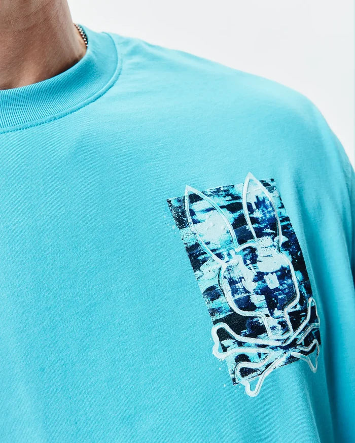 Aqua jersey Mens Isaac Relaxed Fit Tee with a left chest graphic print featuring a distressed blue and black Psycho Bunny skull logo outlined in white.