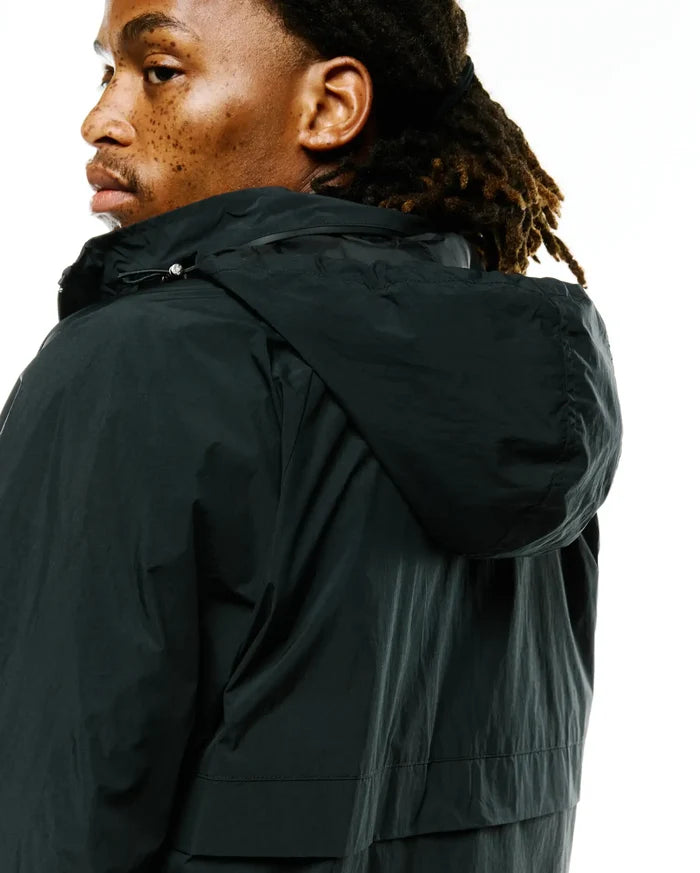 Psycho Bunny's Mens Javier Nylon Windbreaker Jacket in dark forest green, featuring a relaxed fit, crinkled nylon fabric, and an adjustable hood with a silver drawstring toggle.