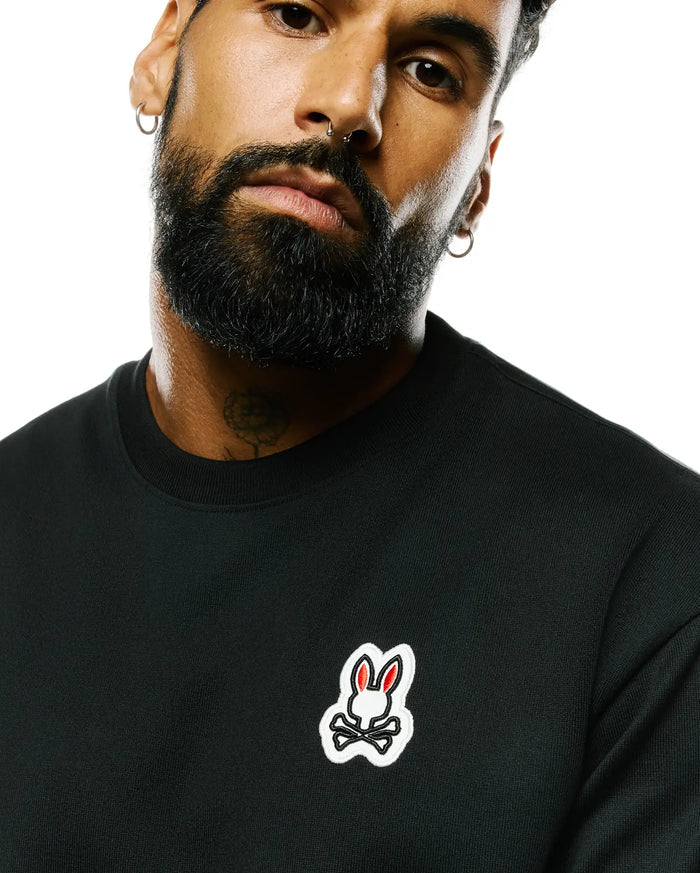 Mens Jaydon Pima Cotton Oversized-Fit Tee in black jersey, featuring a small embroidered Psycho Bunny skull logo on the left chest with white outline and red ears.
