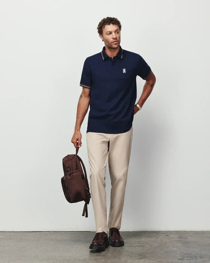 Mens Jaydon Pique Polo in navy, featuring a classic fit, pique texture, and small embroidered Psycho Bunny skull logo on the left chest with gold tipping on the collar and cuffs.