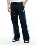 Mens Jaydon Track Pant in navy, featuring a relaxed fit, smooth knit fabric, drawstring waist, and a small embroidered white Psycho Bunny skull logo on the left thigh, with light blue gradient vertical stripes on the sides.