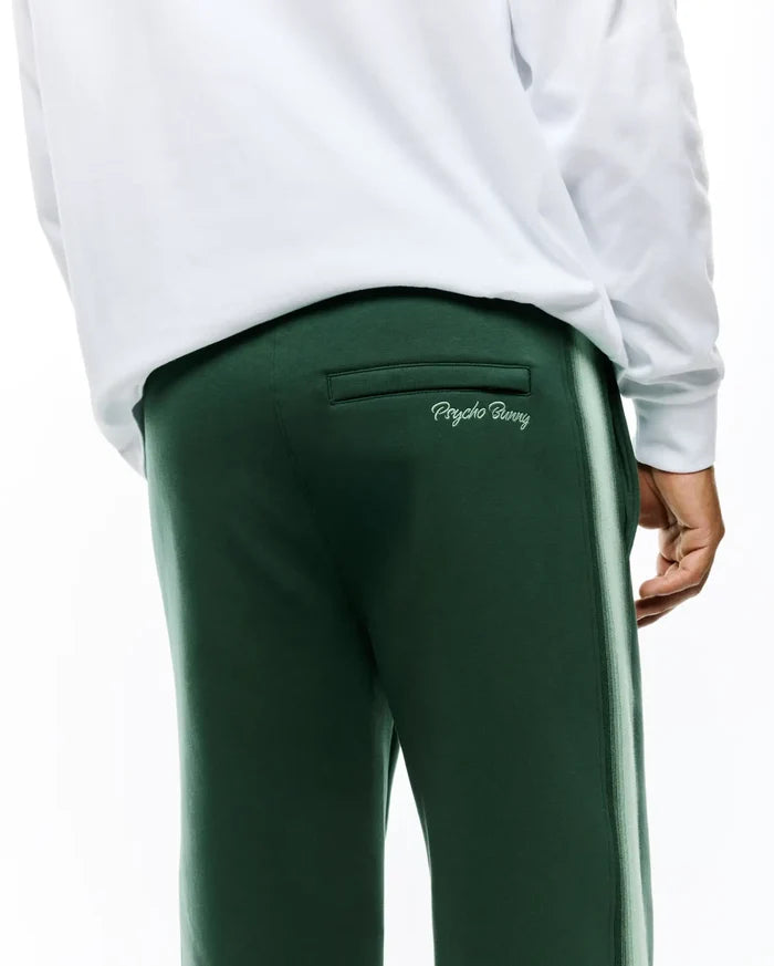 Mens Jaydon Track Pant in dark forest green, featuring a relaxed fit, smooth knit fabric, a multi-tone light green side stripe, and a contrasting embroidered Psycho Bunny script logo above the back pocket.