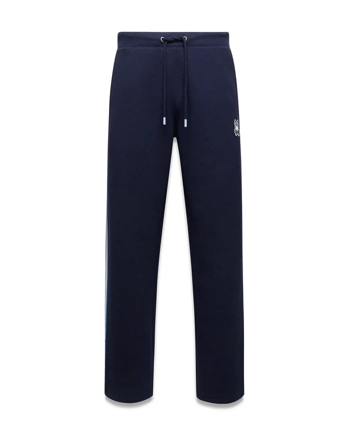 Mens Jaydon Track Pant, navy French terry with a relaxed fit, featuring a white drawstring waist, vertical blue and green side stripe, and a small embroidered white Psycho Bunny skull logo on the right thigh.