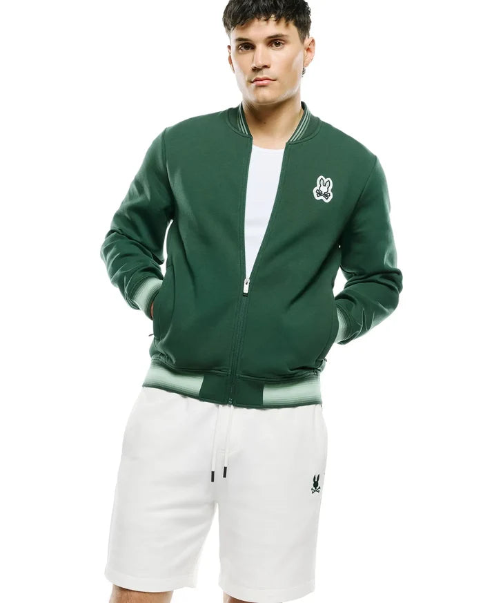 Mens Jaydon Track Jacket, dark green smooth knit, classic fit, full zip, striped ribbed collar, cuffs, and hem, with an embroidered white Psycho Bunny skull logo on the left chest.