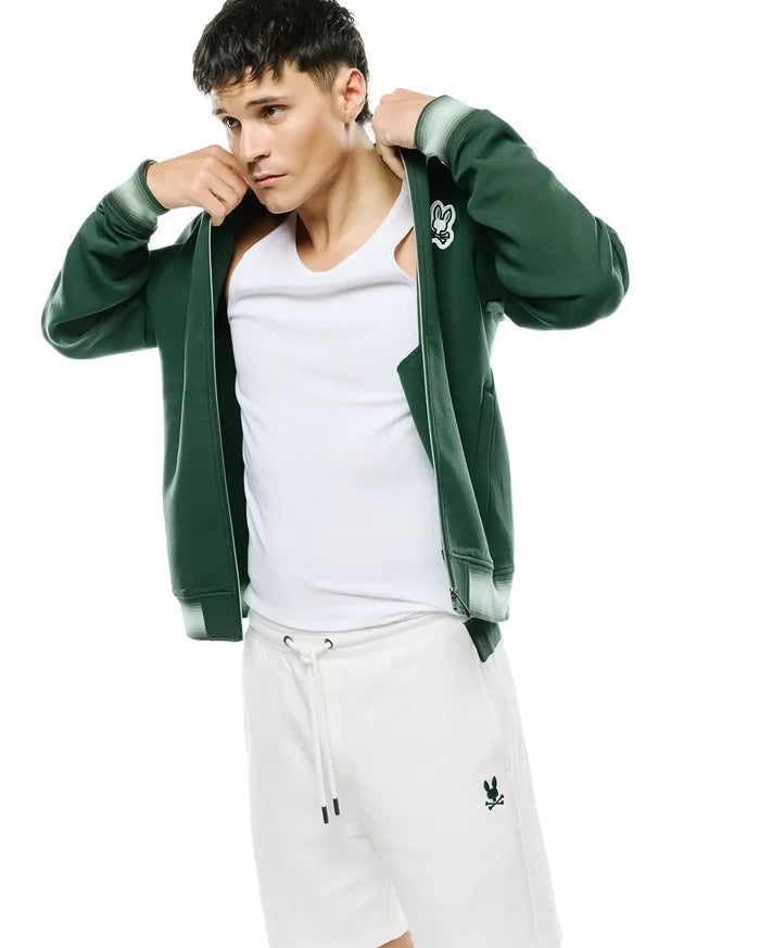 Dark green Mens Jaydon Track Jacket with white embroidered Psycho Bunny chest logo, light green striped cuffs, paired with white ribbed tank top and white drawstring shorts with a green bunny logo.