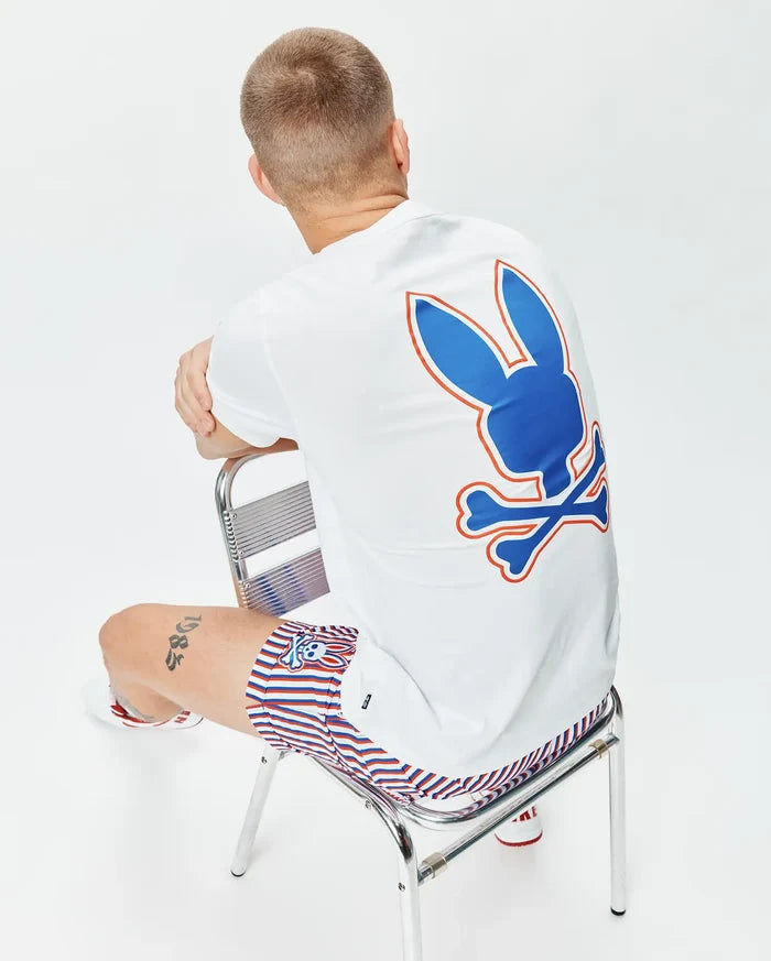 Mens John Back Graphic Tee, a white classic fit jersey t-shirt with a large blue and orange Psycho Bunny skull logo graphic on the back, paired with red, white, and blue striped shorts featuring a small bunny skull logo.