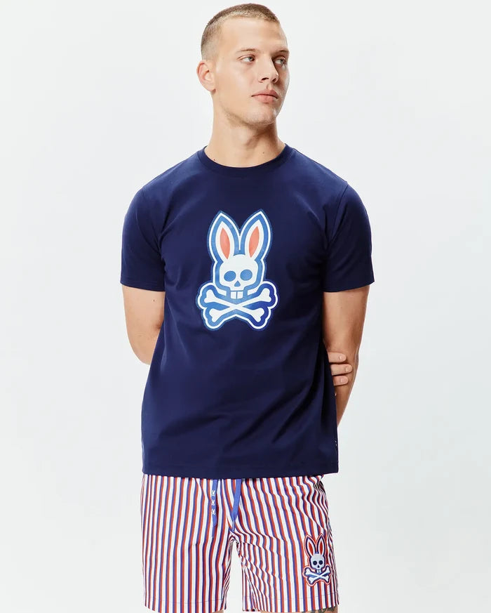 Mens John Graphic Tee, a classic fit navy blue jersey knit t-shirt featuring a large white, light blue, and orange Psycho Bunny skull graphic on the chest and a smaller one on the upper back.