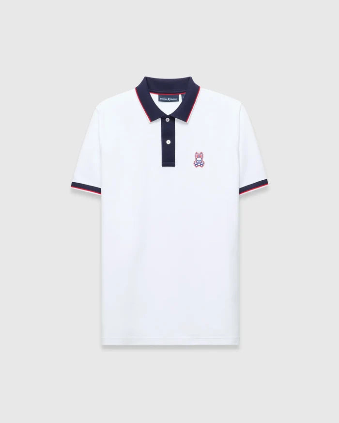 Mens John Pique Polo, a classic fit white pique polo with navy collar and placket, red tipping, navy ribbed cuffs with red stripe, and an embroidered Psycho Bunny skull logo on the left chest.