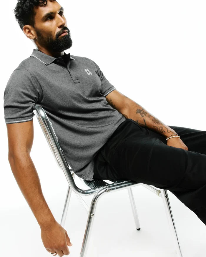 MENS JOJI PERFORMANCE POLO, a dark grey pique knit polo with a classic fit, white tipping on the collar and sleeve cuffs, and a small embroidered Psycho Bunny skull logo on the left chest.