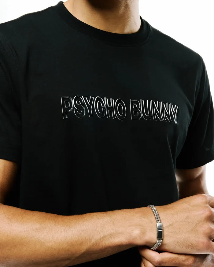 Mens Joji Wordmark Graphic Tee, a black classic fit jersey knit t-shirt featuring a prominent silver outlined Psycho Bunny wordmark graphic on the chest and a small bunny skull logo on the sleeve.