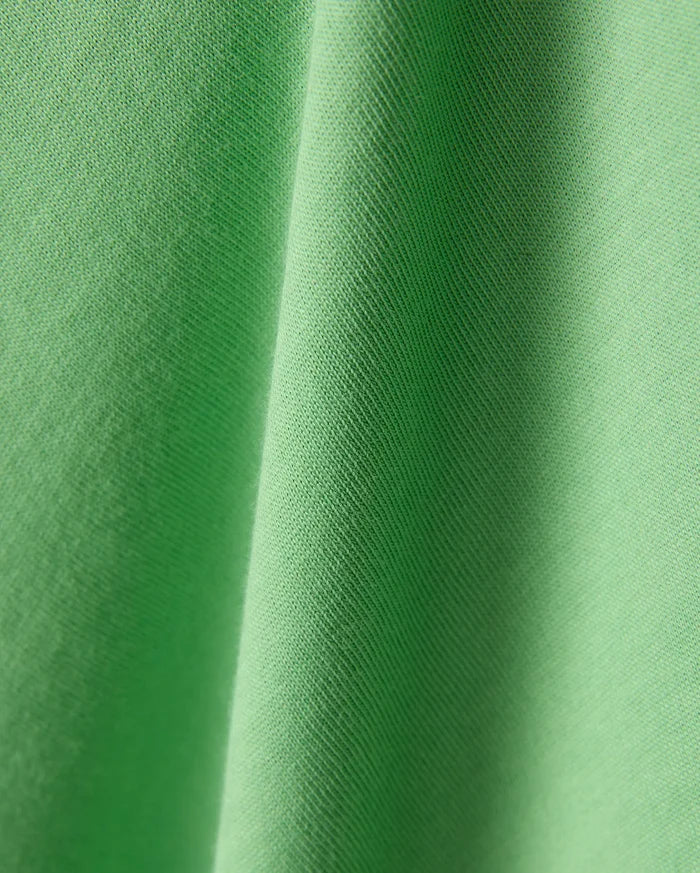 Mens Joji Wordmark Graphic Tee in a vibrant, eye-catching lime green jersey knit fabric, showcasing a fine, soft texture with subtle diagonal ribbing and elegant, flowing folds.
