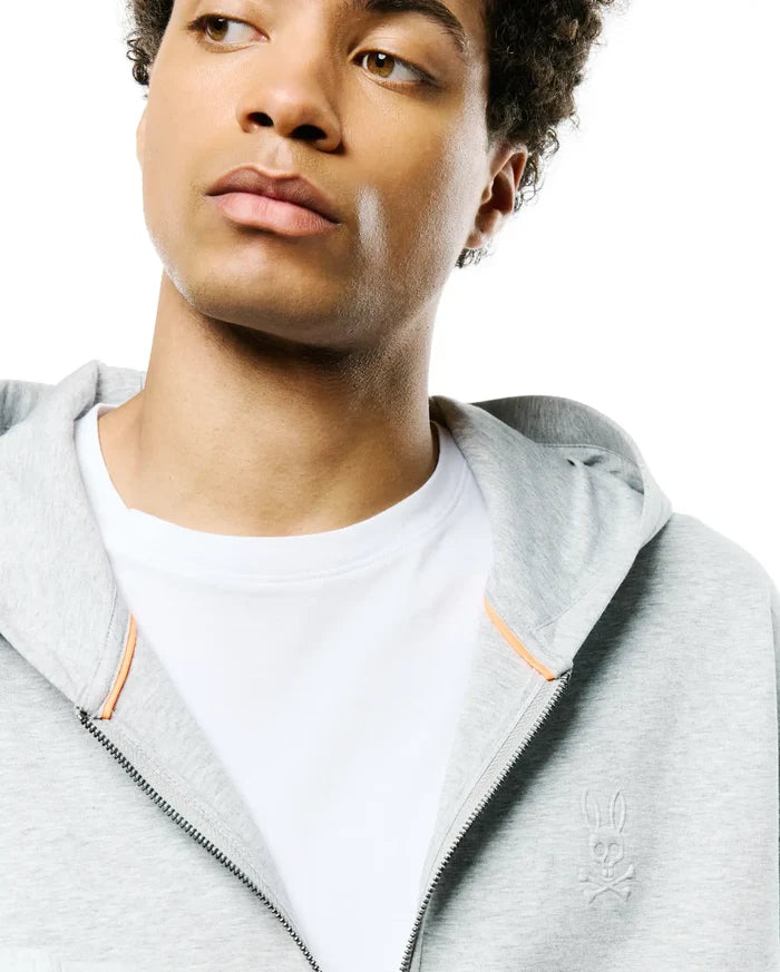Mens Jonathan Zip Hoodie, heather grey French terry, featuring a full zip, subtle orange inner placket trim, and a tonal embroidered Psycho Bunny skull logo on the left chest.
